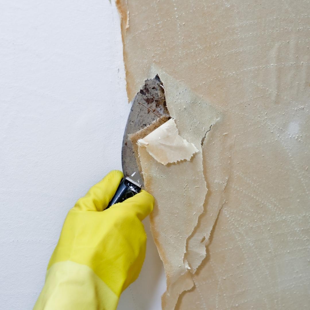 hand in yellow glove removing wallpaper